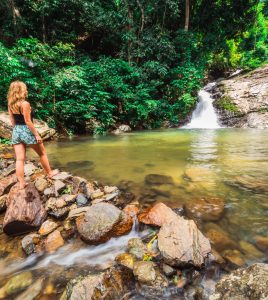 Girl,Standing,And,Looking,At,A,Waterfall,And,Small,Pool